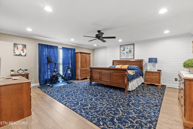 bedroom featuring ceiling fan, wooden walls, ornamental molding, and light wood-type flooring