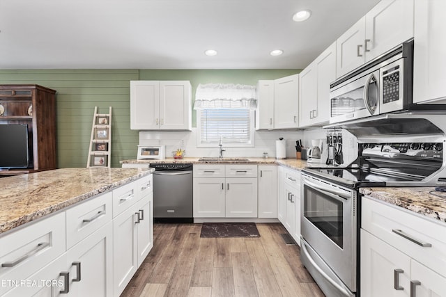 kitchen featuring white cabinets, sink, appliances with stainless steel finishes, and light hardwood / wood-style flooring