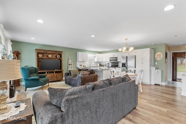 living room featuring wooden walls, an inviting chandelier, and light wood-type flooring