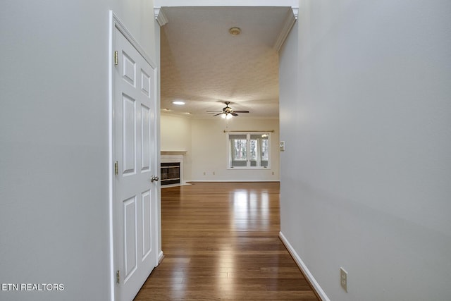 hallway featuring crown molding, dark wood-type flooring, and a textured ceiling