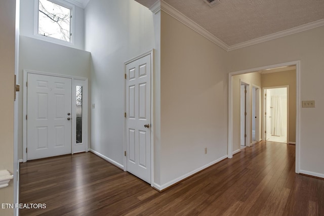 foyer with a high ceiling, a textured ceiling, dark hardwood / wood-style floors, and crown molding