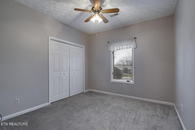 unfurnished bedroom with a textured ceiling, light colored carpet, and ceiling fan