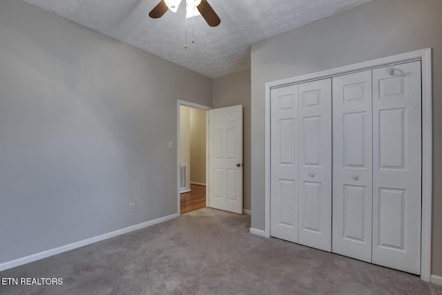 unfurnished bedroom with a closet, ceiling fan, light colored carpet, and a textured ceiling