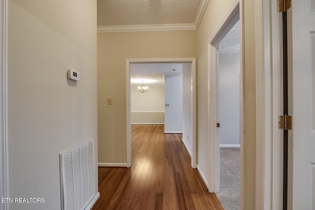 corridor featuring wood-type flooring, a textured ceiling, and crown molding