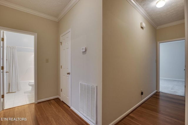 hall featuring wood-type flooring, a textured ceiling, and ornamental molding