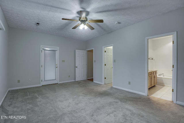 unfurnished bedroom with ceiling fan, a textured ceiling, ensuite bathroom, and light carpet