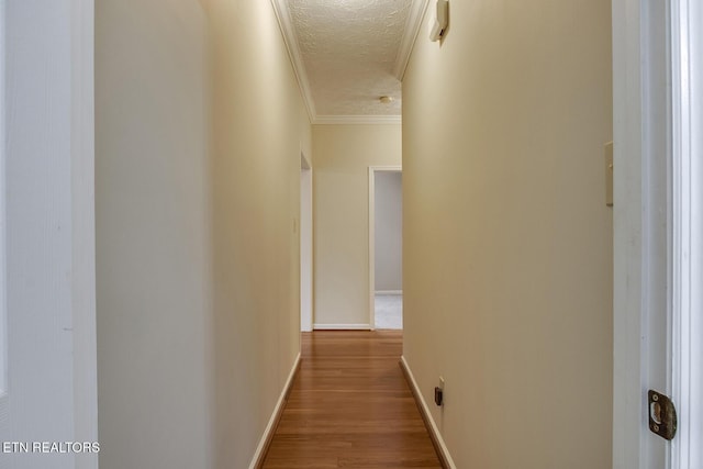 hallway featuring hardwood / wood-style flooring, a textured ceiling, and crown molding