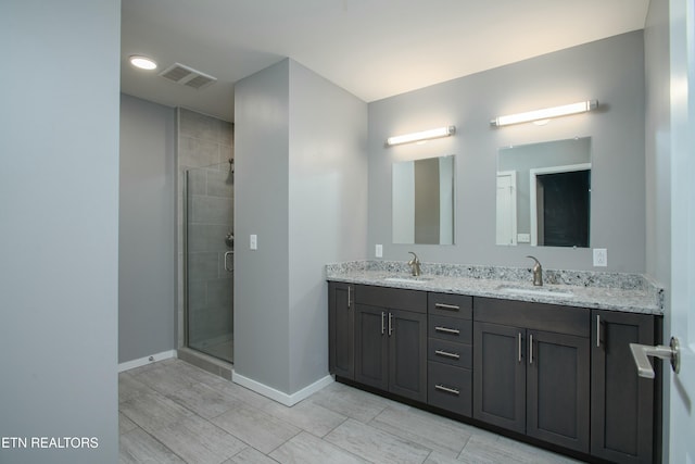 bathroom featuring a shower with door and vanity