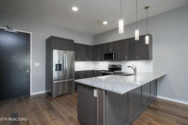 kitchen featuring stainless steel appliances, backsplash, hanging light fixtures, and kitchen peninsula