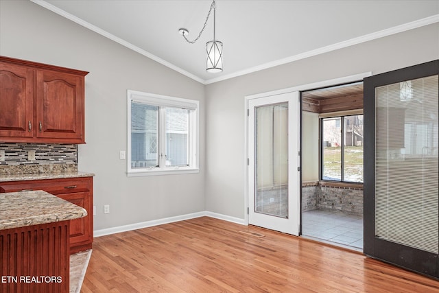 dining room with ornamental molding, light hardwood / wood-style flooring, lofted ceiling, and plenty of natural light