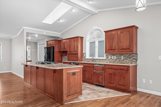 kitchen with light hardwood / wood-style floors, a center island, black fridge, lofted ceiling with skylight, and backsplash