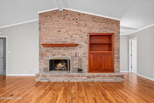 unfurnished living room featuring a fireplace, lofted ceiling with beams, crown molding, and light hardwood / wood-style flooring