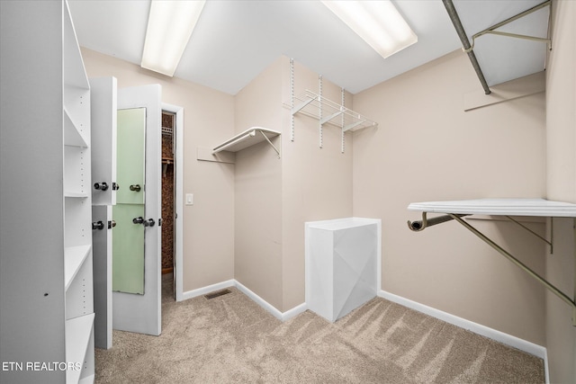 walk in closet featuring light colored carpet