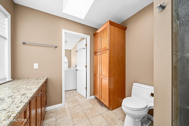 bathroom featuring toilet, a skylight, tile patterned floors, washer / clothes dryer, and vanity