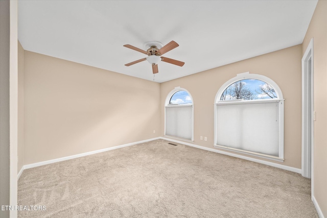 empty room featuring ceiling fan and light carpet