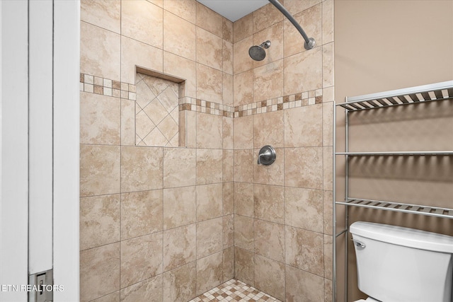 bathroom featuring a tile shower and toilet