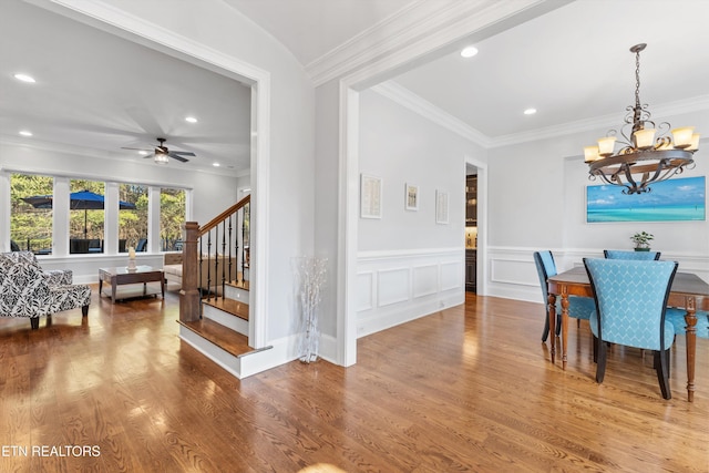 dining space with ceiling fan with notable chandelier, ornamental molding, and hardwood / wood-style flooring