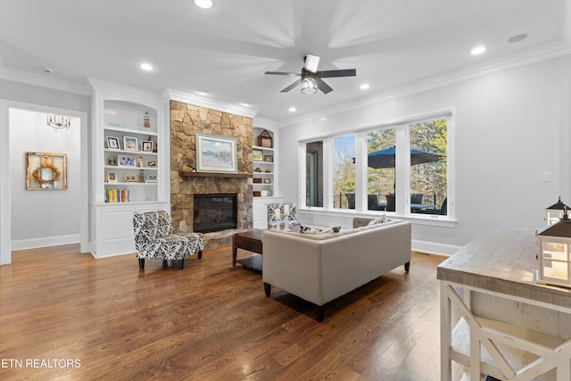 living room featuring crown molding, ceiling fan, dark hardwood / wood-style floors, a fireplace, and built in features