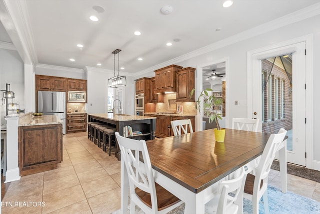 tiled dining area featuring sink, ceiling fan, and crown molding