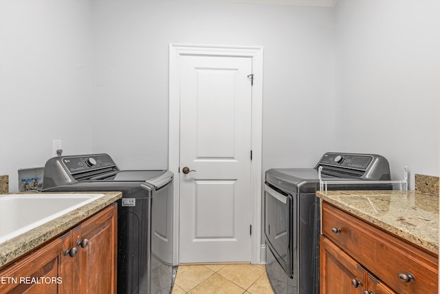 laundry room with light tile patterned flooring, washing machine and clothes dryer, and cabinets