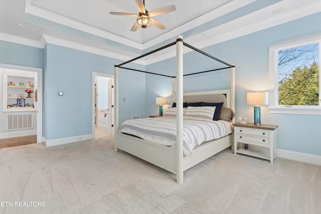 carpeted bedroom with ceiling fan, ensuite bathroom, ornamental molding, and a raised ceiling