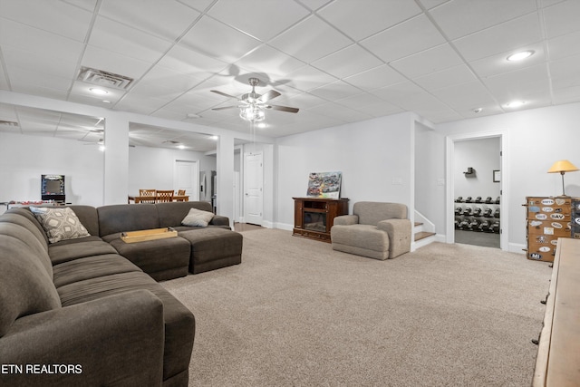 carpeted living room with a drop ceiling and ceiling fan