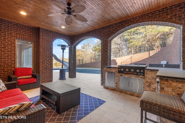 view of patio / terrace featuring exterior kitchen, an outdoor living space, ceiling fan, and a grill