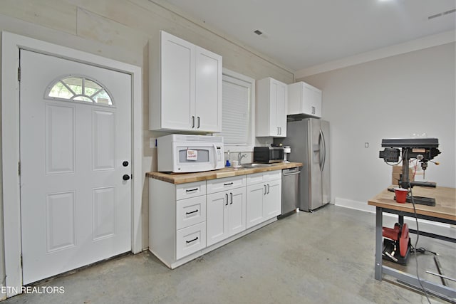 kitchen with sink, white cabinetry, stainless steel appliances, and wooden counters