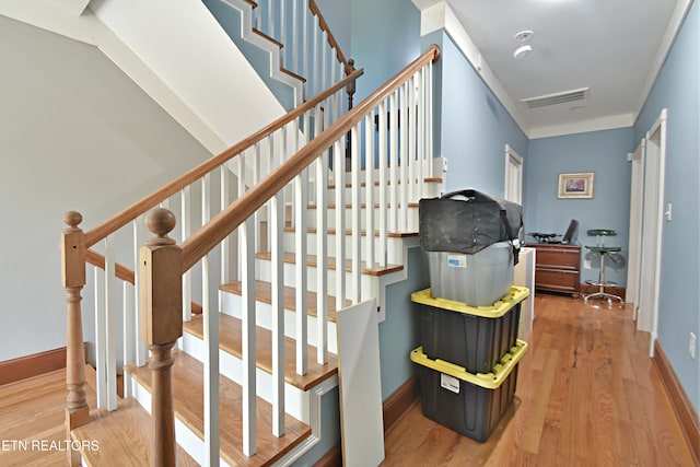 stairs with hardwood / wood-style flooring and ornamental molding