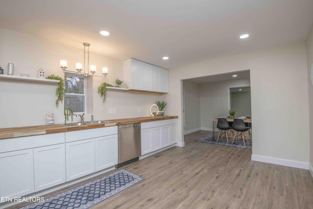 kitchen featuring stainless steel dishwasher, white cabinetry, hanging light fixtures, and wooden counters