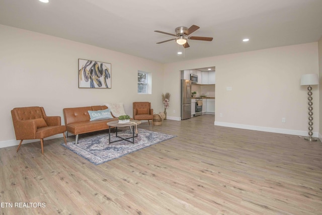 living room with light hardwood / wood-style floors and ceiling fan