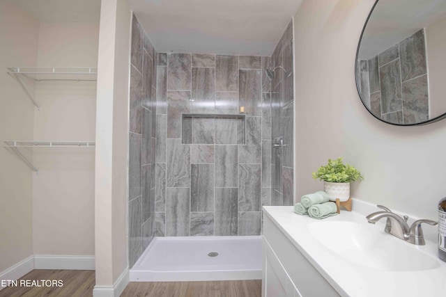 bathroom with vanity, a tile shower, and wood-type flooring