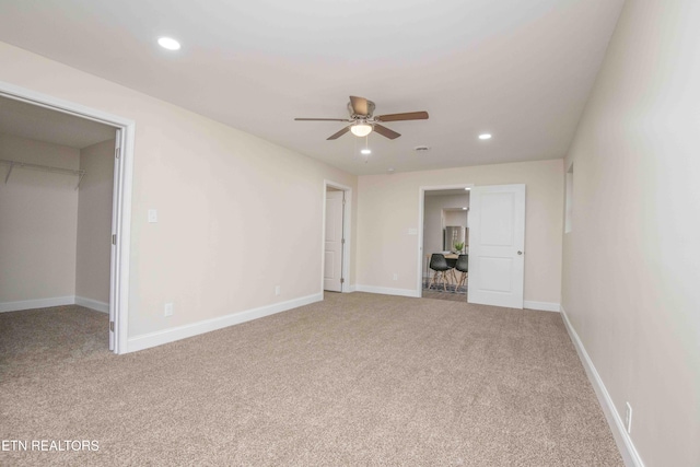 unfurnished bedroom with ceiling fan, a walk in closet, light carpet, and a closet