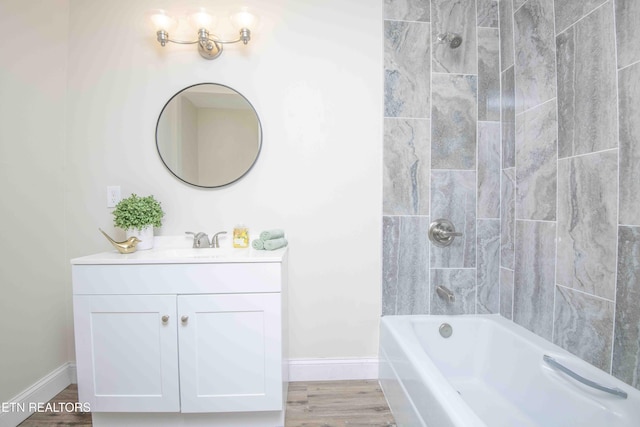 bathroom featuring wood-type flooring, vanity, and tiled shower / bath