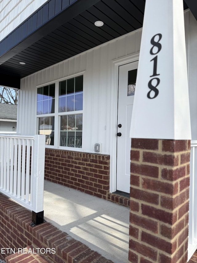 entrance to property with brick siding and a porch