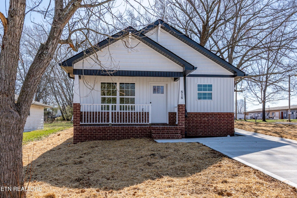 bungalow-style home with brick siding, a porch, and board and batten siding