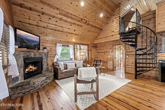 living room with high vaulted ceiling, wood ceiling, a stone fireplace, and wood walls