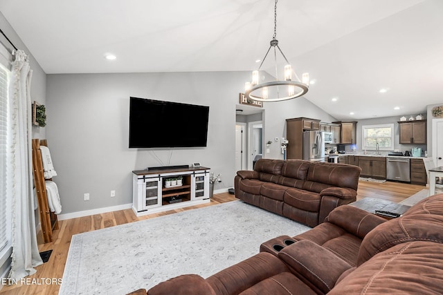 living room featuring sink, light hardwood / wood-style flooring, vaulted ceiling, and an inviting chandelier