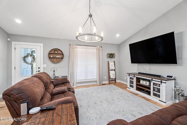 living room featuring light wood-type flooring, vaulted ceiling, and a notable chandelier