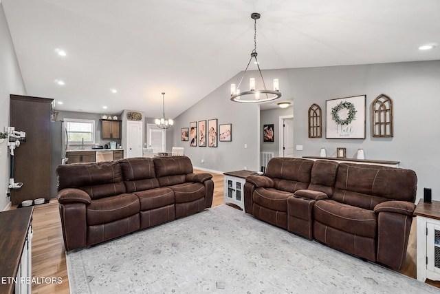 living room featuring sink, light hardwood / wood-style flooring, lofted ceiling, and a notable chandelier