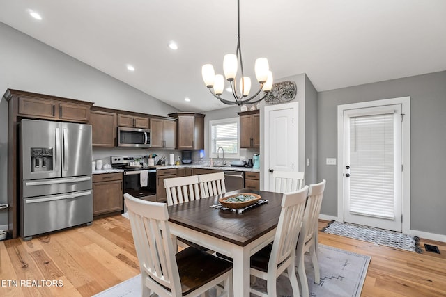 dining room with vaulted ceiling, light wood-type flooring, sink, and an inviting chandelier