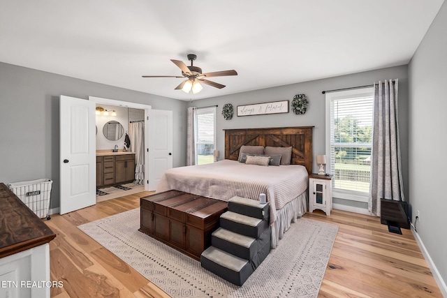 bedroom with ensuite bath, ceiling fan, and light hardwood / wood-style floors