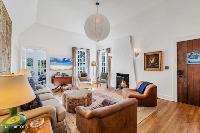 living room featuring light wood-type flooring, a fireplace, and vaulted ceiling