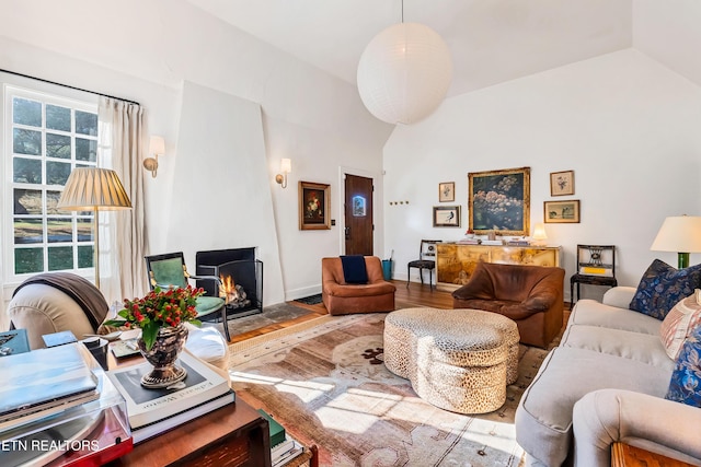 living room with a large fireplace, wood-type flooring, and vaulted ceiling