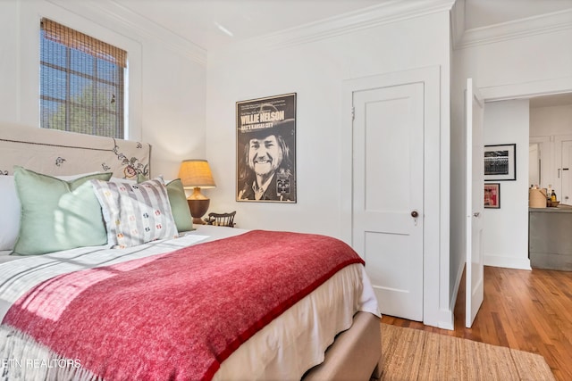 bedroom with light wood-type flooring and crown molding