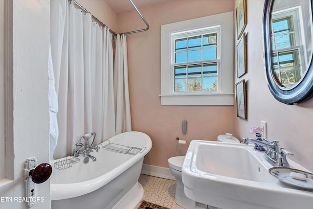 bathroom with tile patterned floors, a tub to relax in, a healthy amount of sunlight, and sink