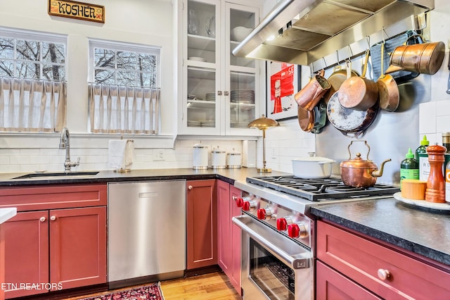 kitchen with sink, light hardwood / wood-style flooring, appliances with stainless steel finishes, tasteful backsplash, and extractor fan