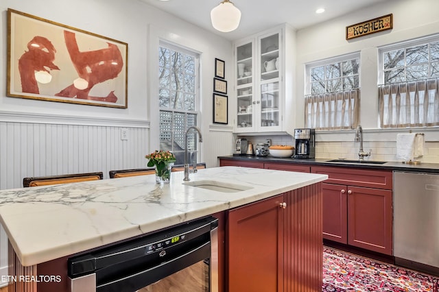 kitchen with black dishwasher, stainless steel dishwasher, a kitchen island with sink, and sink