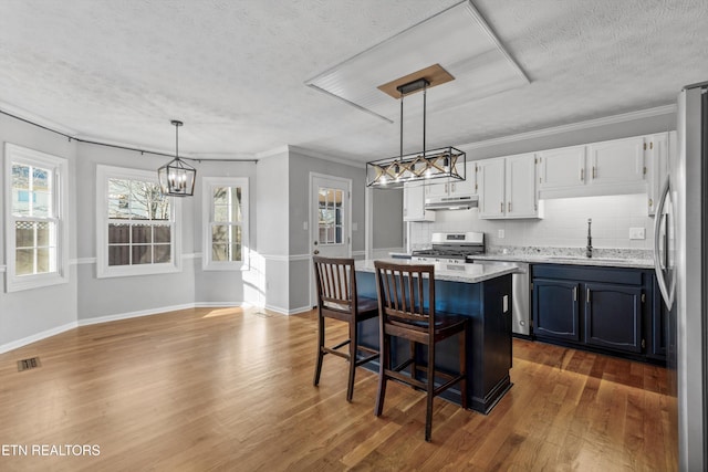 kitchen featuring white cabinetry, sink, stainless steel appliances, pendant lighting, and decorative backsplash