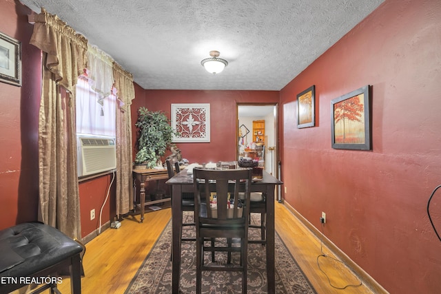 dining space featuring hardwood / wood-style flooring, cooling unit, and a textured ceiling